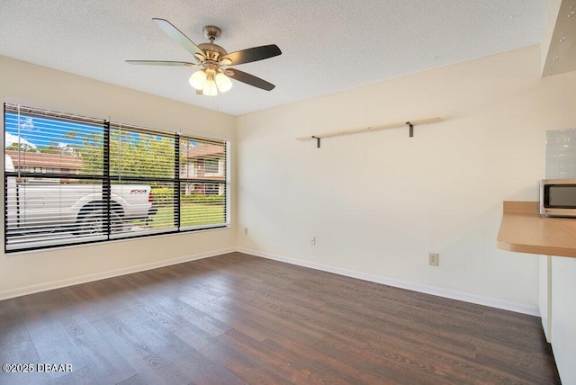 empty room featuring ceiling fan, a textured ceiling, baseboards, and wood finished floors