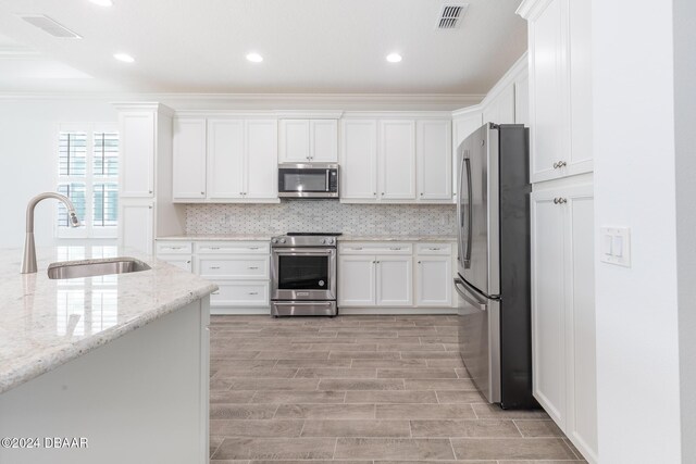 544 Good Life Way, Daytona Beach, FL 32124 - kitchen with appliances with stainless steel finishes, a sink, white cabinetry, crown molding, and light stone countertops