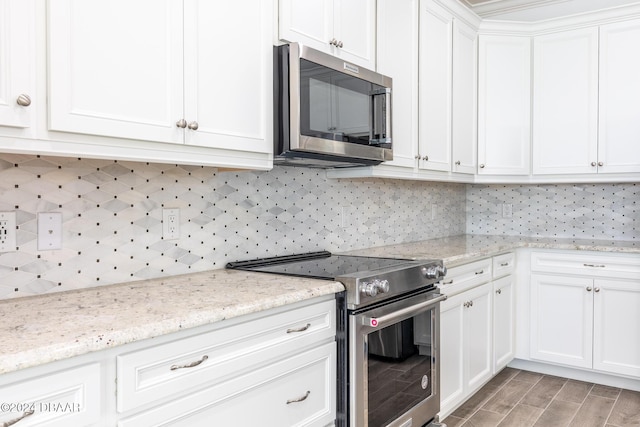 544 Good Life Way, Daytona Beach, FL 32124 - kitchen featuring appliances with stainless steel finishes, white cabinetry, decorative backsplash, light wood-style flooring, and light stone counters