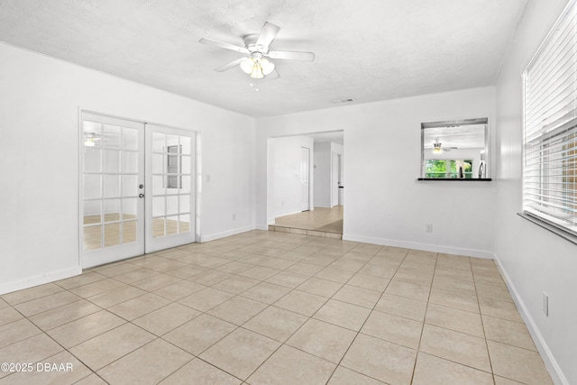 tiled spare room with ceiling fan, a textured ceiling, and french doors