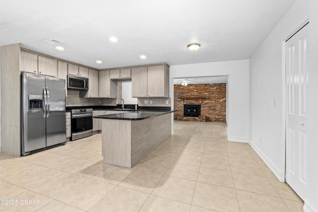 kitchen with a center island, appliances with stainless steel finishes, light tile patterned floors, decorative backsplash, and sink