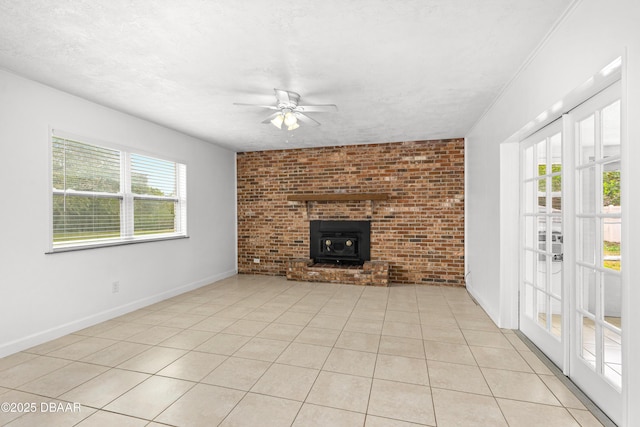 unfurnished living room featuring a textured ceiling, brick wall, light tile patterned floors, a wood stove, and ceiling fan