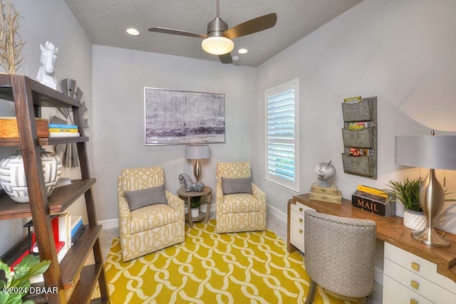 living area featuring ceiling fan and a textured ceiling