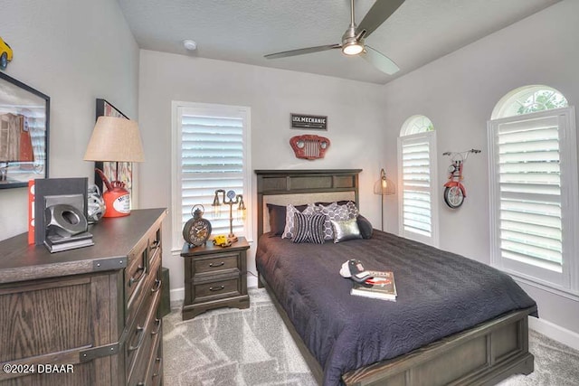 carpeted bedroom featuring multiple windows, ceiling fan, and a textured ceiling