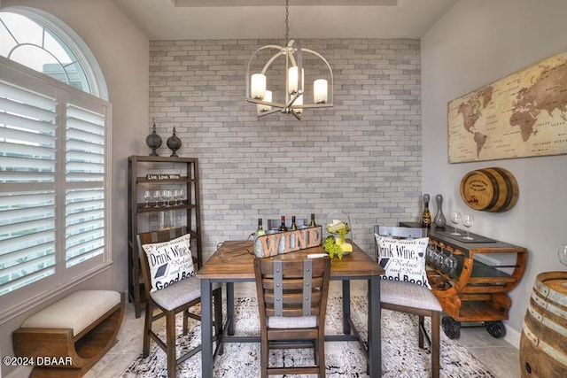 dining space with brick wall, light tile patterned floors, and a notable chandelier