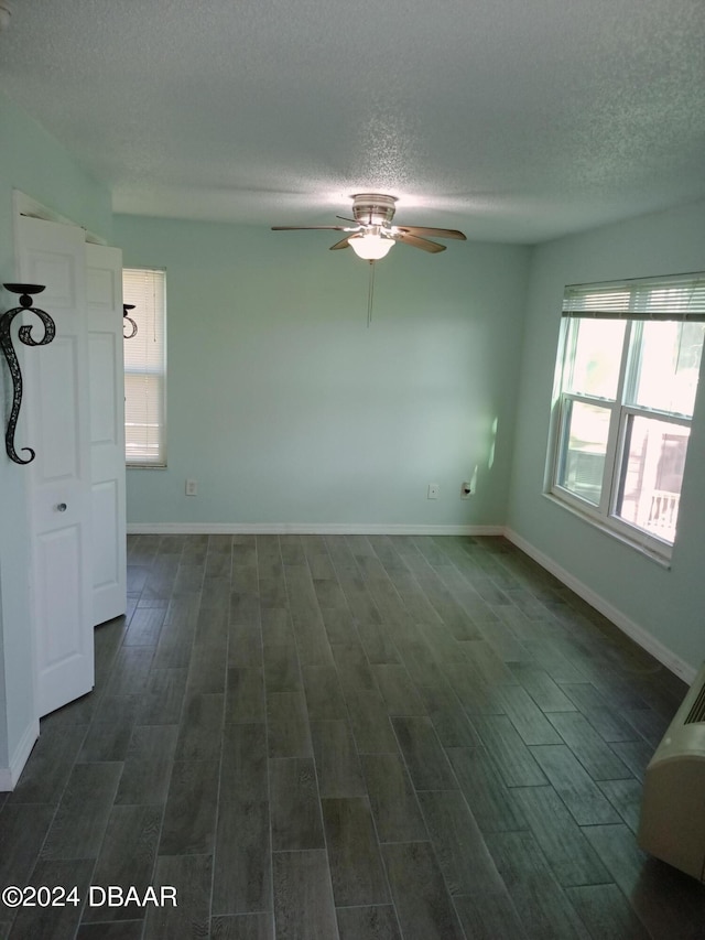 empty room with dark wood-type flooring, a textured ceiling, and ceiling fan