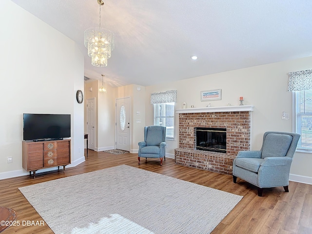 living room featuring baseboards, plenty of natural light, wood finished floors, and a brick fireplace