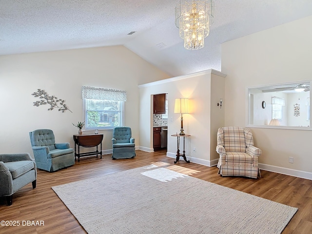 sitting room with lofted ceiling, visible vents, a textured ceiling, wood finished floors, and baseboards