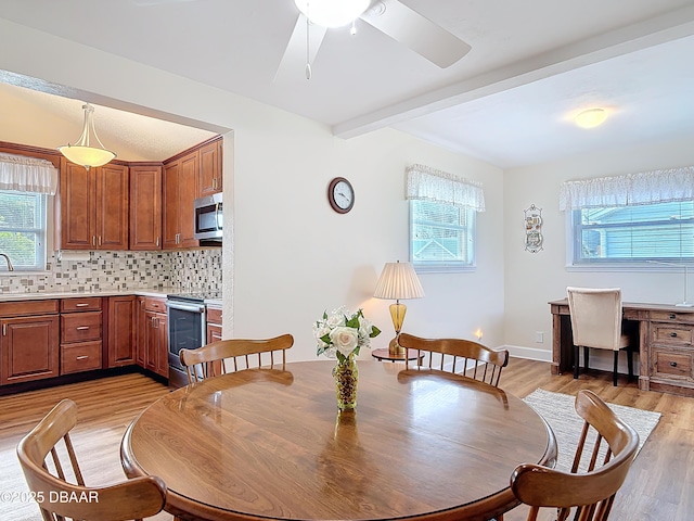 dining area with light wood finished floors, baseboards, a ceiling fan, and beamed ceiling