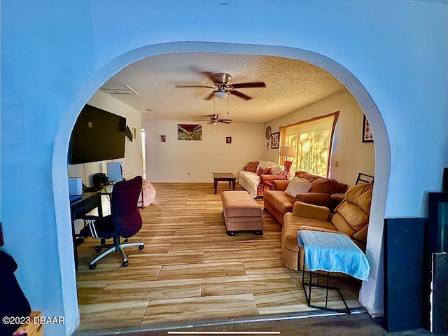 living room featuring hardwood / wood-style floors, ceiling fan, and a textured ceiling