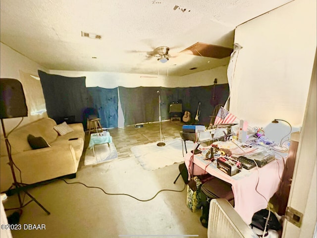 interior space featuring ceiling fan, concrete floors, and a textured ceiling