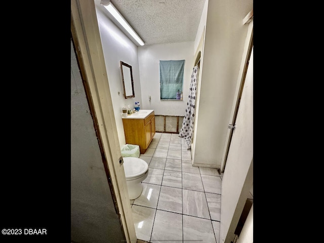 bathroom with walk in shower, tile patterned flooring, a textured ceiling, vanity, and toilet