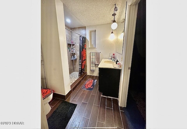 bathroom with a shower with curtain, vanity, a textured ceiling, hardwood / wood-style floors, and toilet