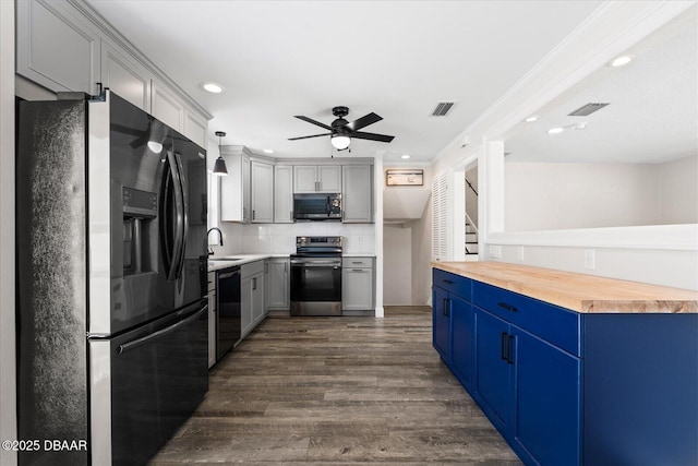 kitchen with butcher block countertops, a sink, visible vents, dark wood-style floors, and black appliances