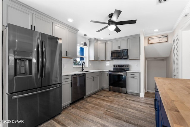 kitchen featuring decorative backsplash, wood counters, appliances with stainless steel finishes, dark wood-type flooring, and pendant lighting