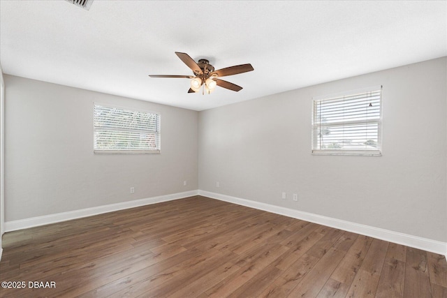 unfurnished room featuring dark wood-style floors, a ceiling fan, and baseboards