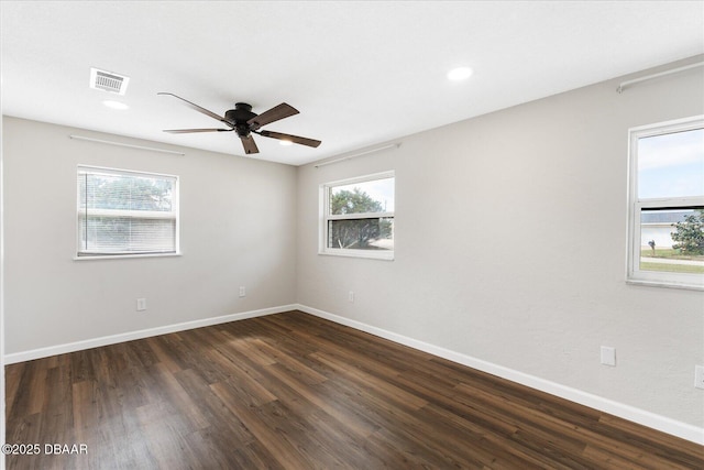 empty room featuring a ceiling fan, baseboards, visible vents, and dark wood-style flooring