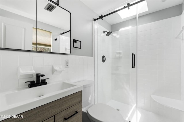 bathroom featuring a stall shower, visible vents, toilet, vanity, and tile walls