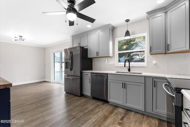 kitchen featuring stainless steel appliances, hanging light fixtures, backsplash, gray cabinetry, and a sink