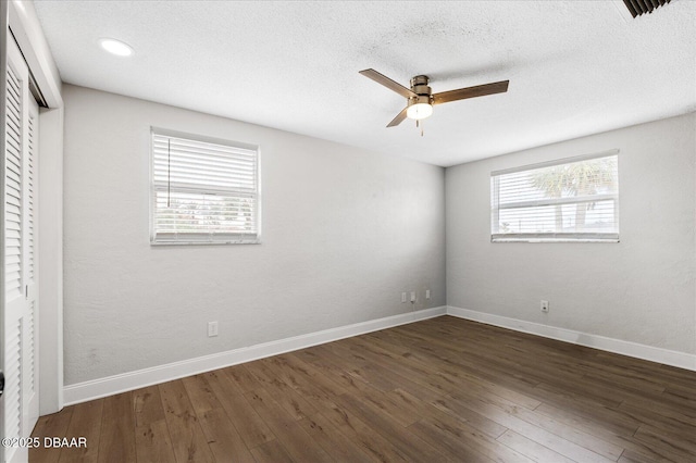 unfurnished bedroom featuring dark wood-type flooring, multiple windows, and baseboards