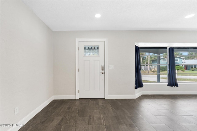 foyer entrance featuring baseboards, dark wood finished floors, and recessed lighting