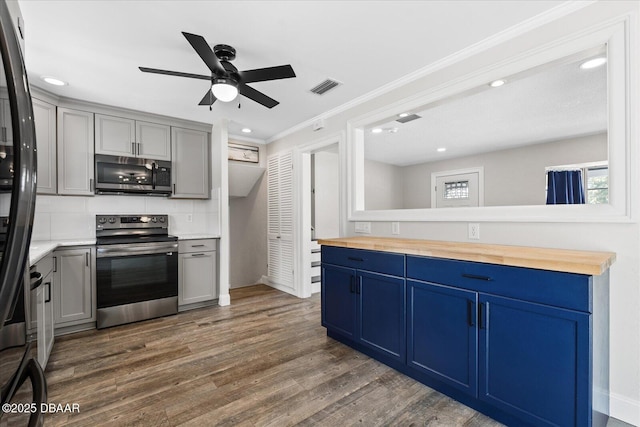 kitchen with tasteful backsplash, visible vents, butcher block countertops, appliances with stainless steel finishes, and dark wood-style flooring