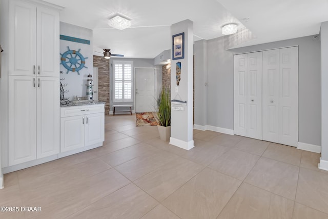 interior space featuring light tile patterned floors, ceiling fan, and white cabinetry