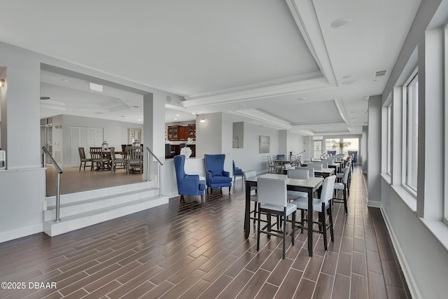 dining area with visible vents, baseboards, a tray ceiling, and wood tiled floor