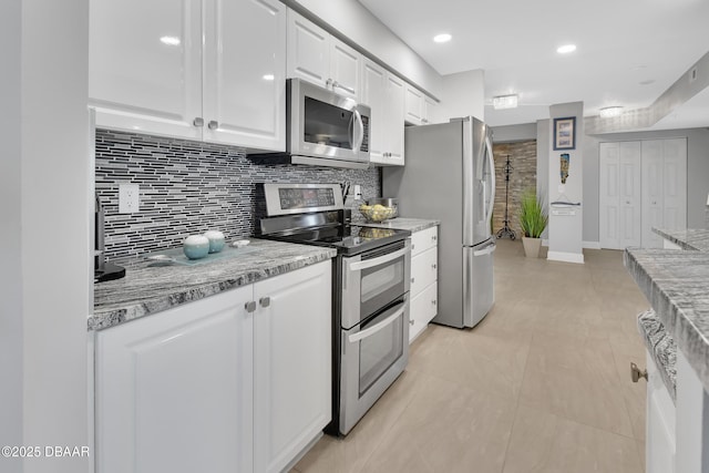 kitchen with stainless steel appliances, tasteful backsplash, and white cabinets