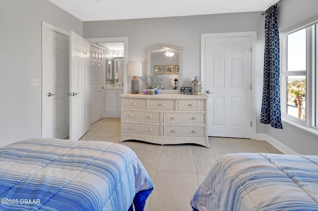 bedroom featuring light tile patterned floors, baseboards, and ensuite bathroom