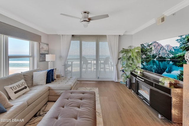 living room with visible vents, ceiling fan, a water view, light wood-type flooring, and ornamental molding