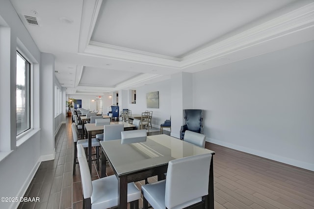 dining room featuring a raised ceiling, baseboards, visible vents, and wood finish floors