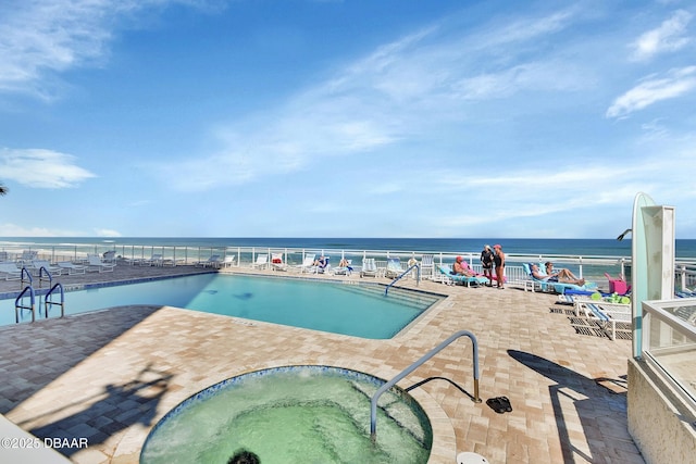 community pool featuring a patio, a water view, and a hot tub