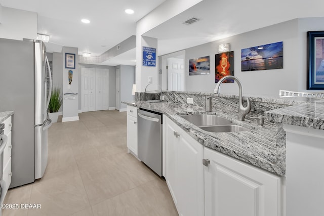 kitchen featuring visible vents, a sink, light stone counters, appliances with stainless steel finishes, and white cabinets