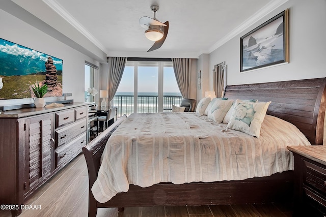 bedroom with access to exterior, wood finished floors, crown molding, and a water view