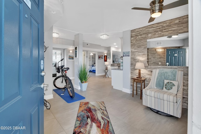 foyer entrance featuring light tile patterned floors, visible vents, baseboards, and a ceiling fan