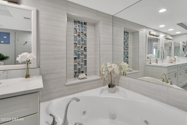 bathroom with recessed lighting, vanity, and a whirlpool tub