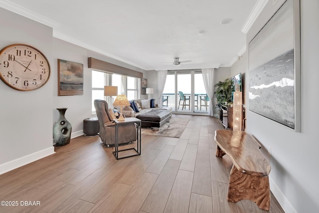 living area with baseboards, wood finished floors, ornamental molding, and a ceiling fan