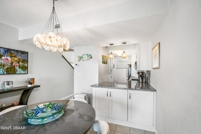 kitchen featuring pendant lighting, white cabinets, dark stone countertops, and freestanding refrigerator