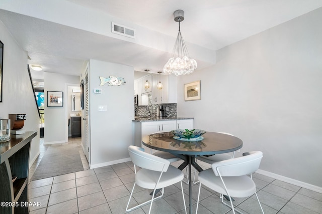 dining room featuring visible vents, a notable chandelier, baseboards, and light tile patterned flooring