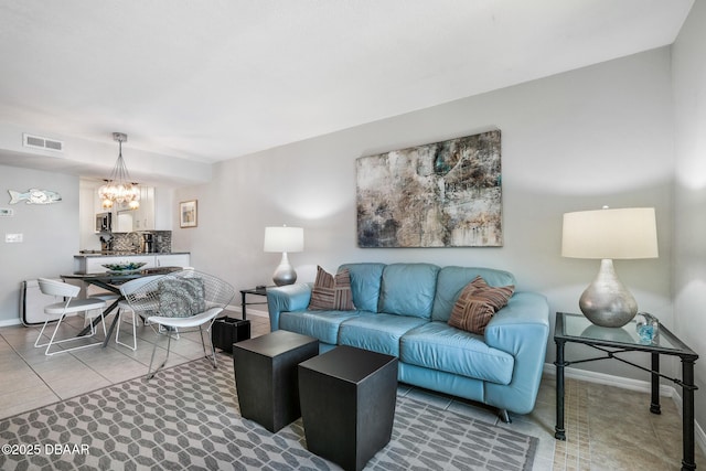 living area featuring baseboards, tile patterned floors, visible vents, and a notable chandelier