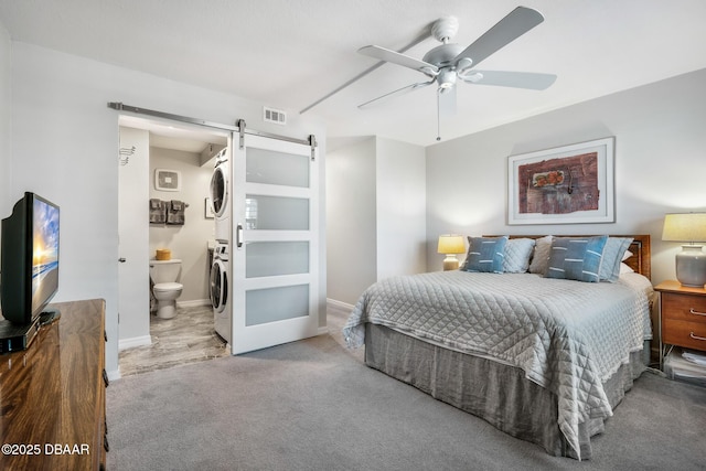 bedroom with stacked washer and dryer, visible vents, a barn door, carpet flooring, and baseboards