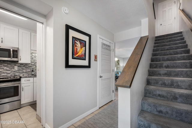 staircase featuring baseboards, a textured ceiling, and tile patterned floors