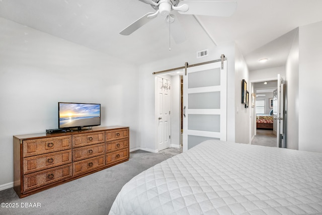 carpeted bedroom featuring a barn door, visible vents, ceiling fan, and baseboards