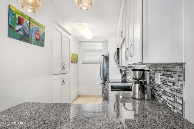 kitchen featuring appliances with stainless steel finishes, backsplash, a sink, and white cabinets