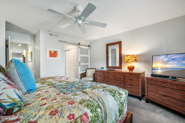 bedroom featuring ceiling fan, a barn door, carpet flooring, visible vents, and a closet