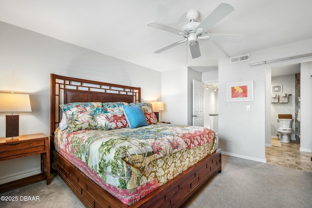 carpeted bedroom with a barn door, visible vents, baseboards, ceiling fan, and ensuite bathroom