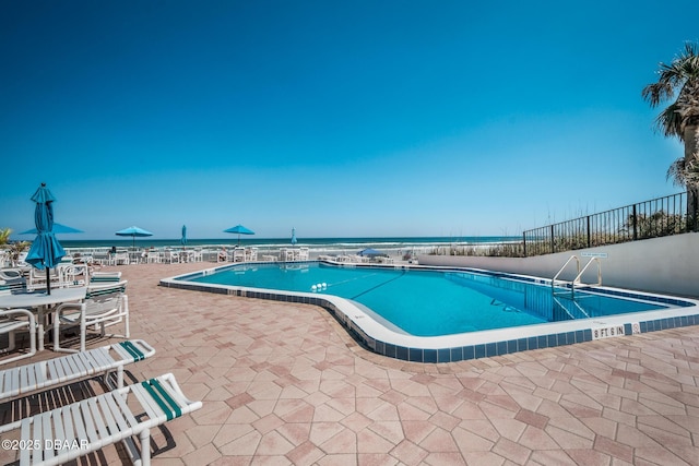 pool featuring a water view, fence, and a patio