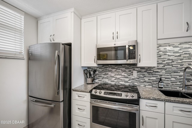 kitchen featuring appliances with stainless steel finishes, backsplash, a sink, and white cabinetry