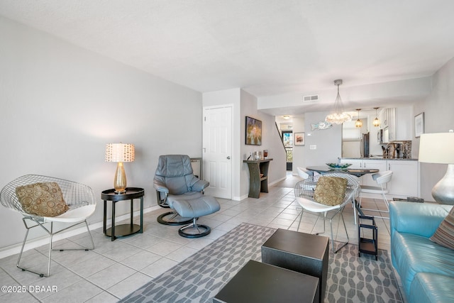 living room with light tile patterned floors, visible vents, baseboards, and a chandelier